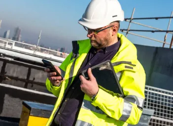 Roofer recording progress on a phone from a scaffolded roof